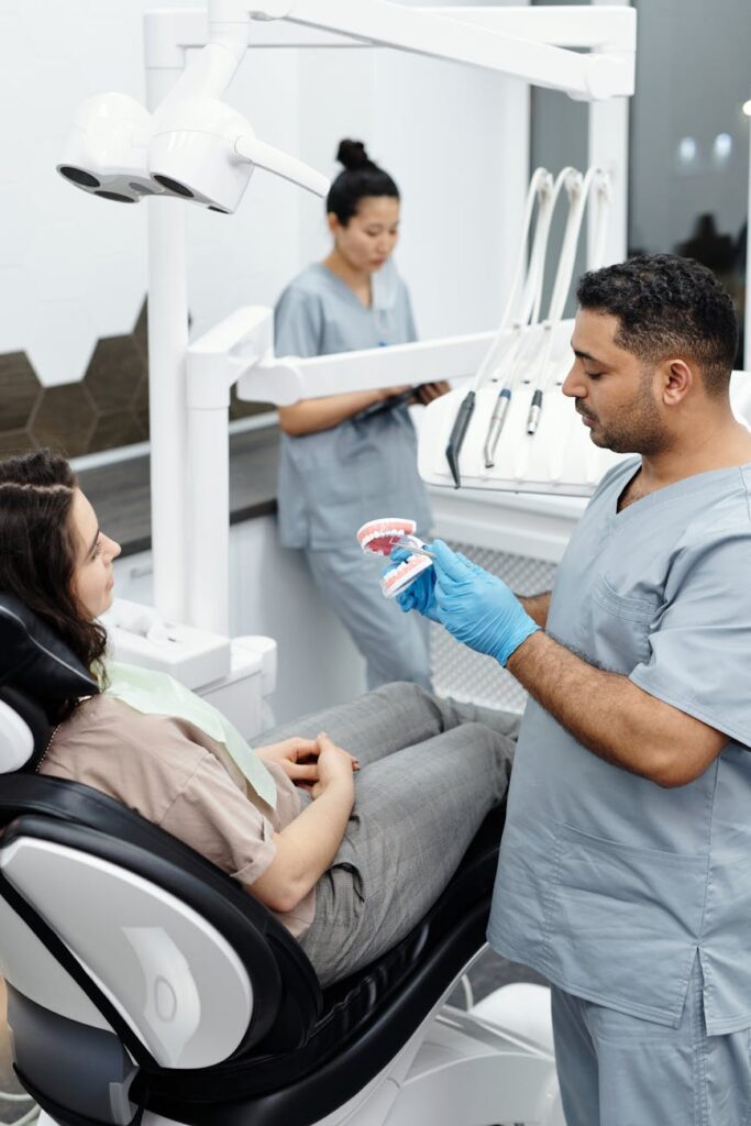 a man in gray scrub suit standing beside a woman on the dental chair